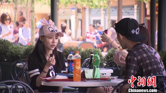 图为上海迪士尼乐园内，游客坐着品尝食物。　徐明睿 摄